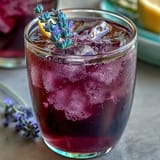 Vibrant purple lemonade refresher infused with lavender syrup and garnished with lemon slices for a cool, floral twist.