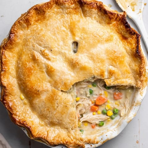 A slice of homemade Chicken Pot Pie is served on a white plate with a fresh green salad on the side.