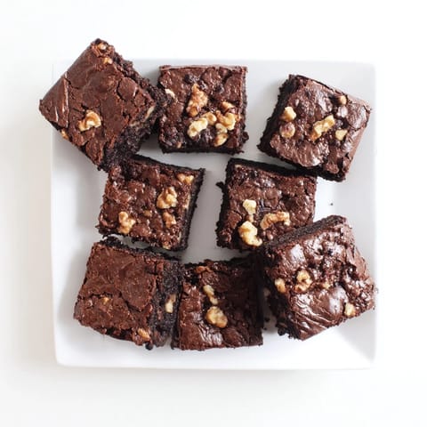 A batch of freshly baked brownies cut into squares, ready to serve with a glass of cold milk.