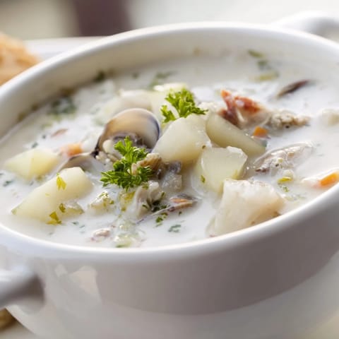 Creamy New England Clam Chowder with tender clams and potatoes in a rustic bowl.