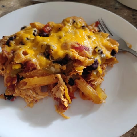Savory Chicken Enchilada Pasta served in a white dish, garnished with fresh cilantro and creamy avocado slices, perfect for a weeknight dinner.  