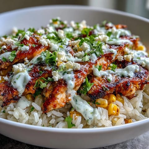 A vibrant bowl of Street Corn Chicken and Rice Bowls features juicy grilled chicken, zesty crema, and fresh cilantro garnish.