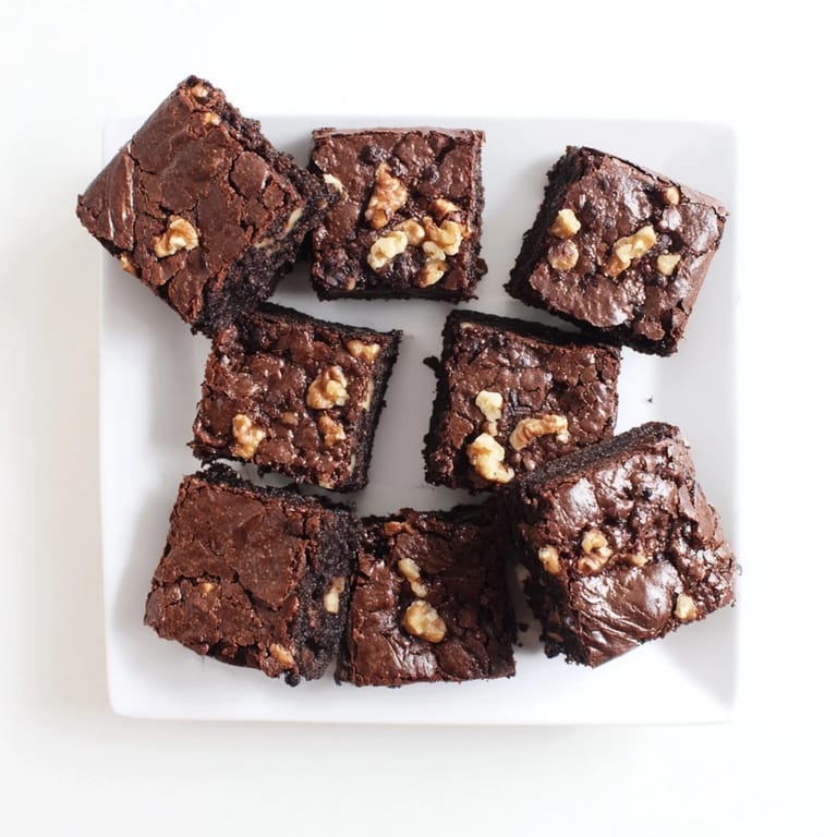 A batch of freshly baked brownies cut into squares, ready to serve with a glass of cold milk.