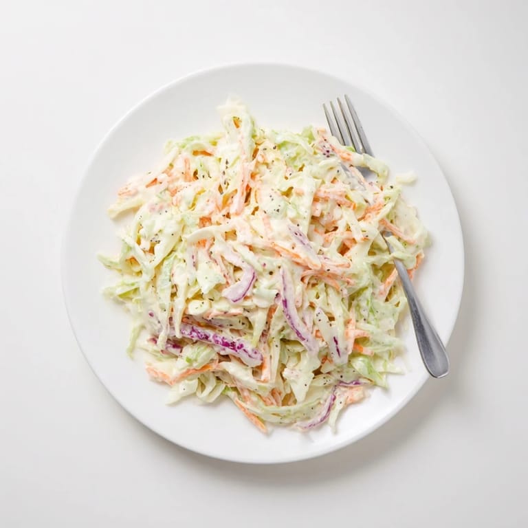 A chilled bowl of Coleslaw tossed with shredded cabbage, carrots, and a creamy dressing, perfect for BBQs.