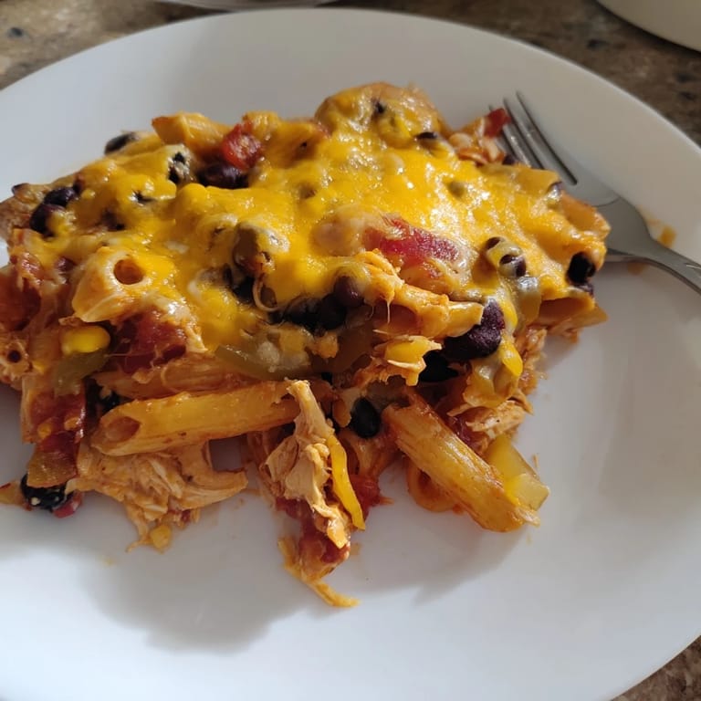 Savory Chicken Enchilada Pasta served in a white dish, garnished with fresh cilantro and creamy avocado slices, perfect for a weeknight dinner.  