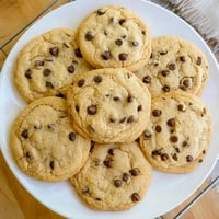 Golden-brown Chocolate Chip Cookies rest on a cooling rack with visible melty semi-sweet chocolate chunks.