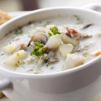 Creamy New England Clam Chowder with tender clams and potatoes in a rustic bowl.