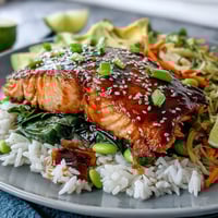 Flaky soy-ginger glazed salmon perches atop fluffy jasmine rice, surrounded by crisp edamame and vibrant bell peppers.