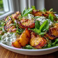 Grilled Peach and Burrata Salad with Honey: juicy, caramelized peaches paired with creamy burrata and fresh arugula.